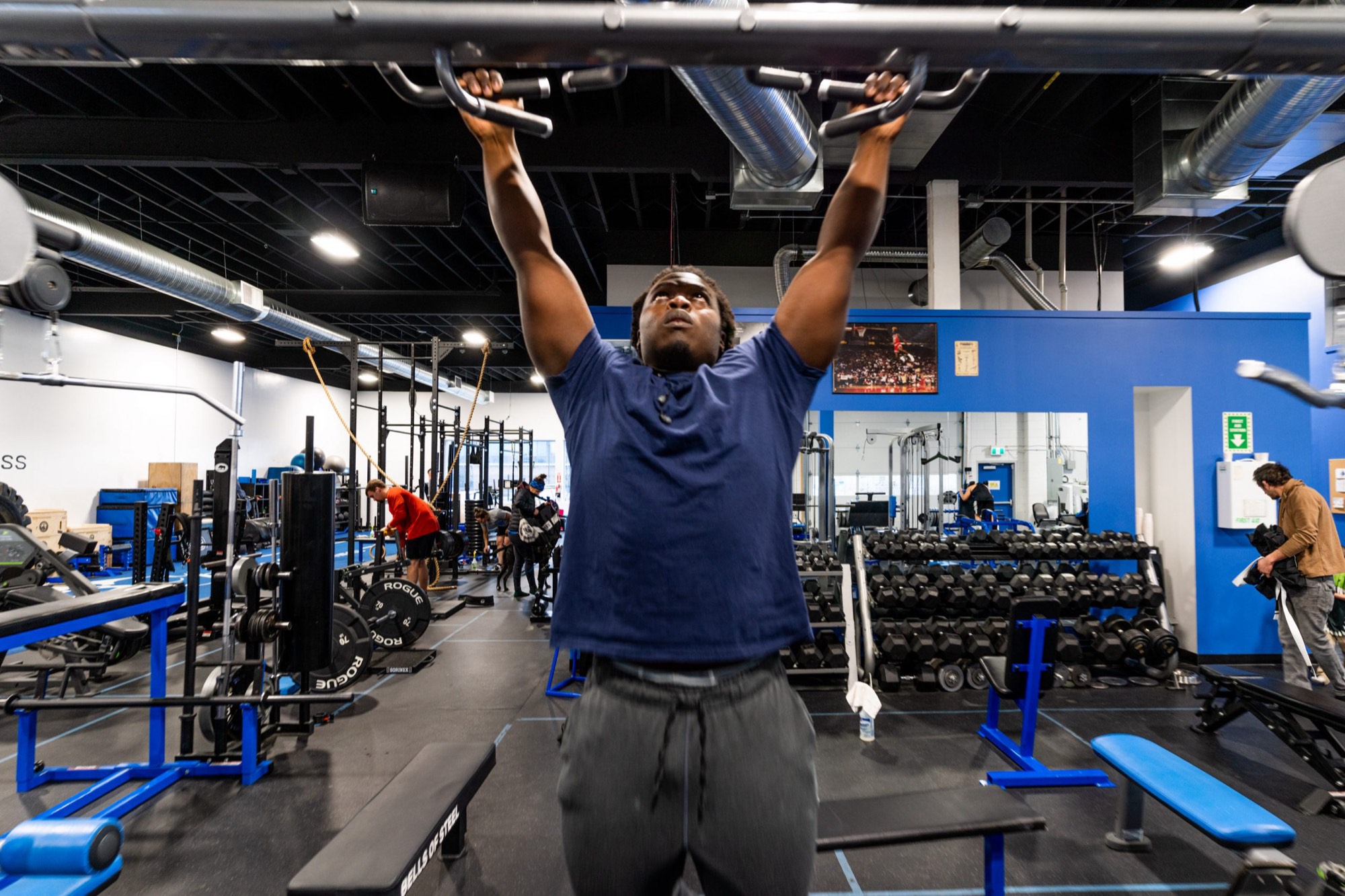 A member does pull-ups over the blue steel floor at Kings Fitness Sunridge